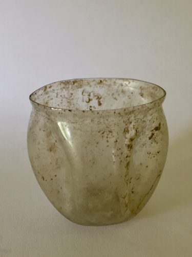 1st or 2nd century CE Roman glass cup with four indented panels. Part of a French early glass collection.